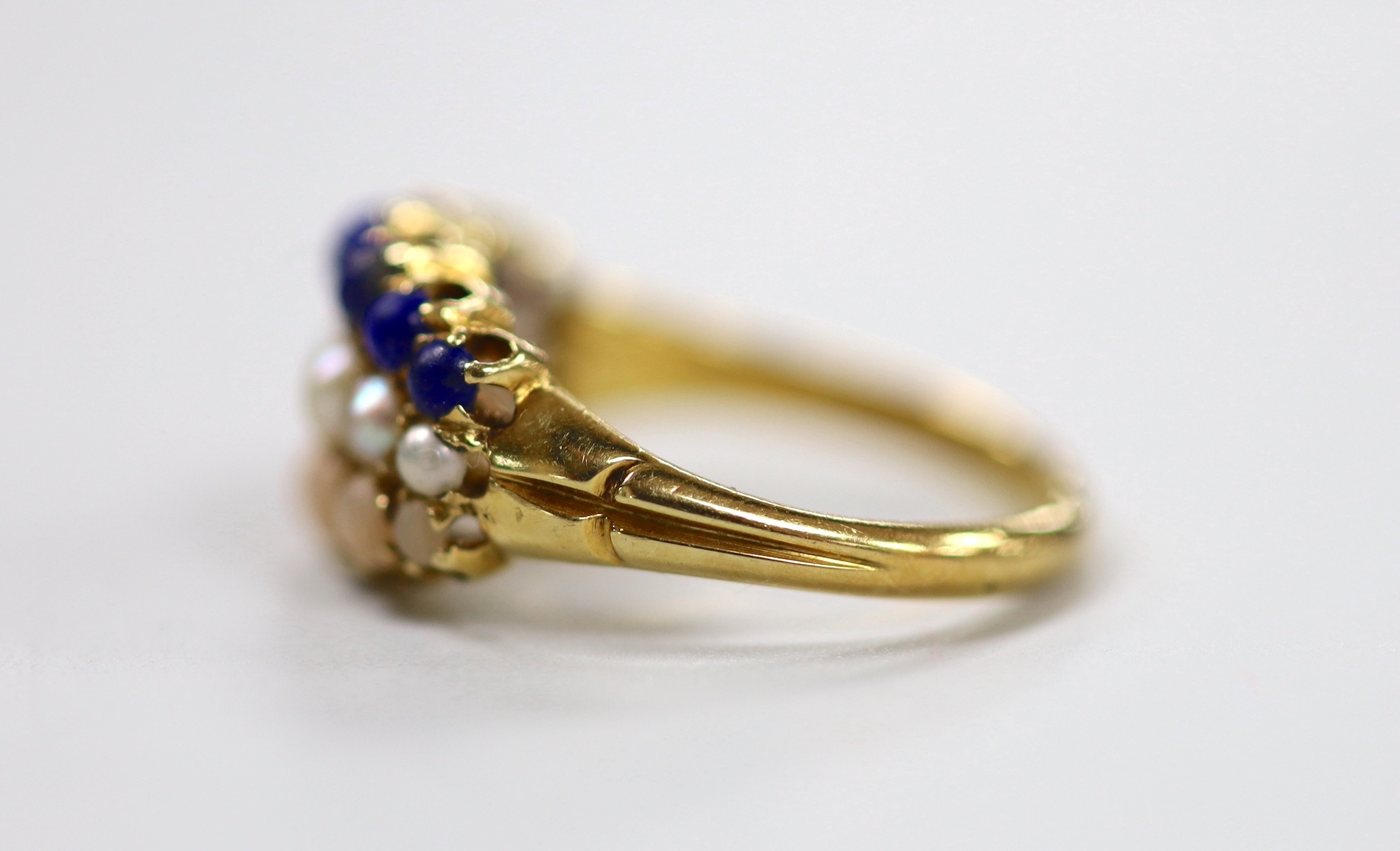 An early to mid 20th century yellow metal and graduated lapis lazuli, split pearl and coral set three row half hoop ring, size L, gross weight 4.3 grams.